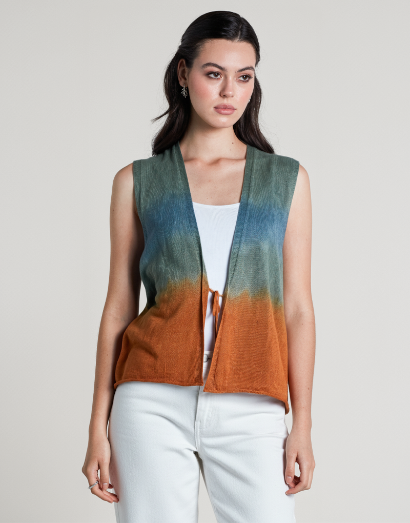 Modelo usando chaleco sin mangas Ada Vest en tonos degradados tierra, azul y verde. Prenda liviana de lino y algodón orgánico con lazo frontal, ideal para looks frescos y sofisticados. Diseño artesanal y atemporal de Anntarah.