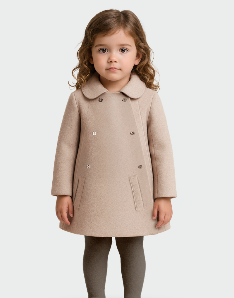 Niña con abrigo beige de lana baby alpaca, diseño clásico de doble botonadura y bolsillos frontales, ideal para moda infantil elegante y sostenible
