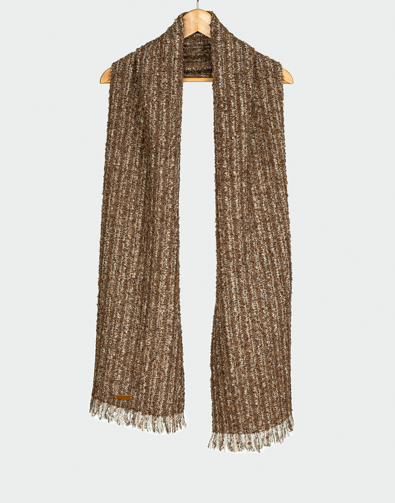 Bufanda de punto acanalado en mezcla de marrón oscuro con crudo y textura jaspeada rústica con flecos finos colgada en gancho de madera