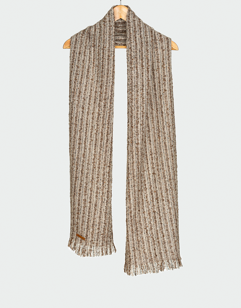 Bufanda acanalada en tejido jaspeado de tonos beige medio y marrón con flecos cortos colgada en gancho de madera